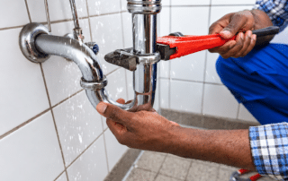 Plumber repairing a leaking sink pipe with a wrench